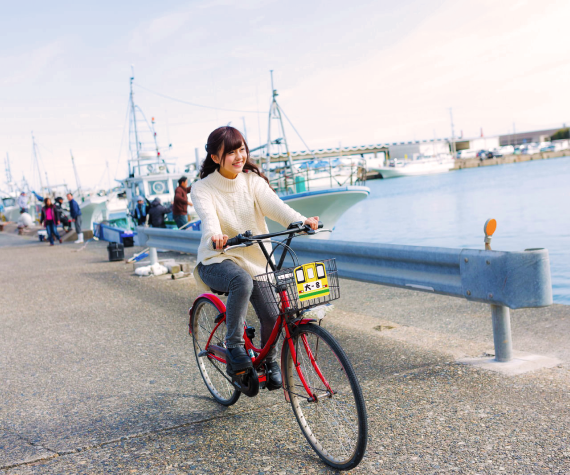 漁港を自転車の乗って走る女性