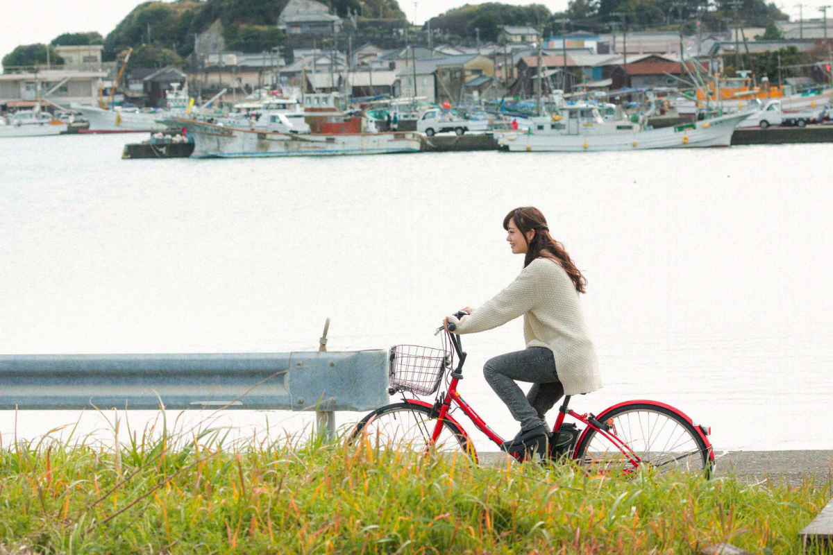ひなた町の海沿いを自転車で走る女性