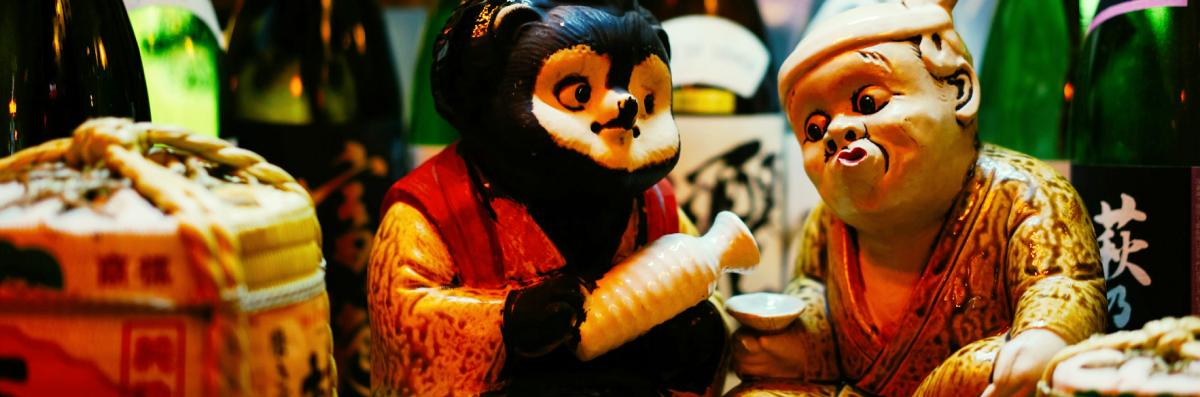 たぬきがひょっとこにお酒を注いでいる置物